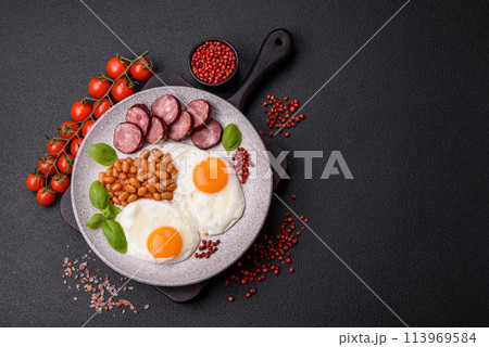 English breakfast with fried eggs, bacon, beans, tomatoes, spices and herbs English breakfast with fried eggs, bacon, beans, tomatoes, spices and herbs 113969584