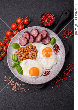 English breakfast with fried eggs, bacon, beans, tomatoes, spices and herbs 113969585