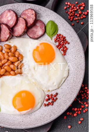 English breakfast with fried eggs, bacon, beans, tomatoes, spices and herbs English breakfast with fried eggs, bacon, beans, tomatoes, spices and herbs 113969588