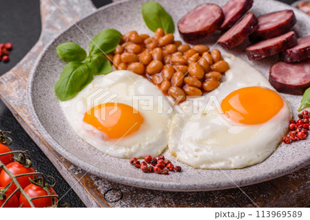 English breakfast with fried eggs, bacon, beans, tomatoes, spices and herbs English breakfast with fried eggs, bacon, beans, tomatoes, spices and herbs 113969589