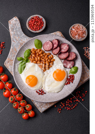 English breakfast with fried eggs, bacon, beans, tomatoes, spices and herbs 113969594