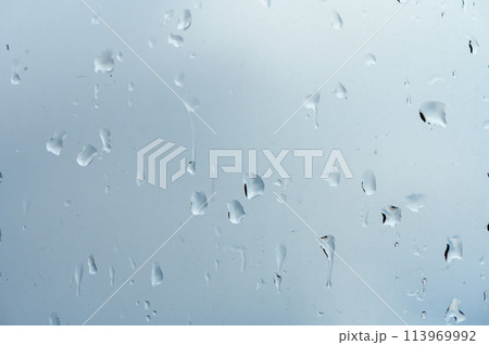 Glass with rain drops against gray background. 113969992