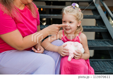 Child girl with cochlear implant with her mother spend time outdoor. Hear impairment and deaf community concept. Deaf and health concept. Disability and inclusion. Copy space 113970611