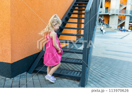 Child girl with hearing aids and cochlear implants having fun outdoor speak and playing. Inclusion and disability. 113970626
