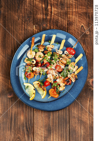 Seafood kebabs on wooden background. Seafood kebabs on wooden background. 113970728
