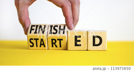 Started and finished symbol. Businessman turns beautiful wooden cubes and changes word Started to Finished. Beautiful yellow table white background. Business started and finished concept. Copy space. 113971650
