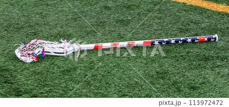 Red white and blue American Flag lacrosse stick on a turf field 113972472