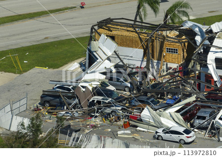 Destroyed by hurricane industrial building with damaged cars under ruins in Florida. Natural disaster and its consequences 113972810