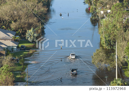 Flooded Florida road with evacuating cars and surrounded with water houses in suburban residential area. Consequences of hurricane natural disaster Flooded Florida road with evacuating cars and surrounded with water houses in suburban residential area. Consequences of hurricane natural disaster 113972968