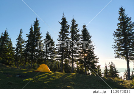 Tourist camping tent on mountain campsite at bright sunny evening. Active tourism and hiking concept Tourist camping tent on mountain campsite at bright sunny evening. Active tourism and hiking concept 113973035