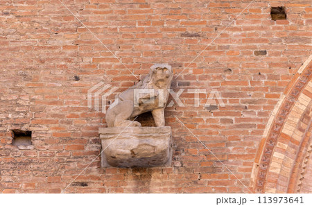 Architectural detail featuring a stone lion sculpture on a brick wall in Bologna 113973641