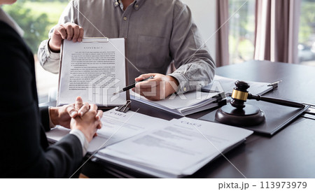 Male lawyer showing contract and pointing the signature box for signing while explaining and consultation about legislation agreement and terms data of business contract to businessman in law firm 113973979
