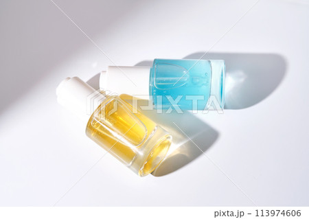 Yellow and blue serums with pipettes against the background of the sun. Yellow and blue serums with pipettes against the background of the sun. 113974606