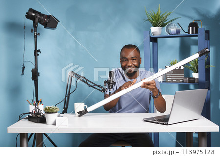 Blogger presenting light tube for videography studio and live streaming review. Internet vlogger showing and discussing professional lightning equipment while looking at camera 113975128