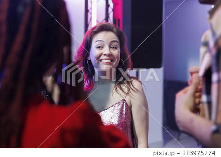 Smiling cheerful woman partying with friends and socializing at nightclub discotheque. Carefree happy girl clubbing and attending disco social gathering event, enjoying nightlife leisure Smiling cheerful woman partying with friends and socializing at nightclub discotheque. Carefree happy girl clubbing and attending disco social gathering event, enjoying nightlife leisure 113975274