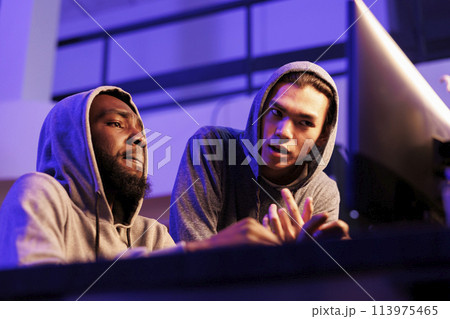 Hackers collaborating while discussing criminal activity and planning cyberattack. African american and asian criminals programming malicious software to break into database Hackers collaborating while discussing criminal activity and planning cyberattack. African american and asian criminals programming malicious software to break into database 113975465