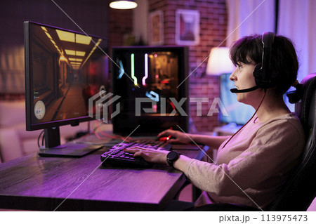 Pro streamer playing videogames on gaming pc as a living, streaming live action tournament online. Gamer enjoying shooting game at computer desk, broadcasting footage for fans Pro streamer playing videogames on gaming pc as a living, streaming live action tournament online. Gamer enjoying shooting game at computer desk, broadcasting footage for fans 113975473