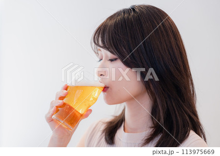 笑顔でビールを飲む若い女性 113975669