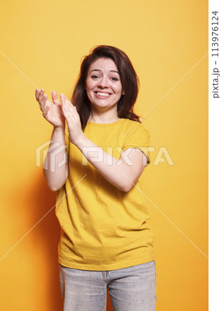 Cheerful female individual clapping hands to celebrate achievement while looking at camera. Caucasian woman with positive emotions applauding and doing appreciation claps for her friend. 113976124