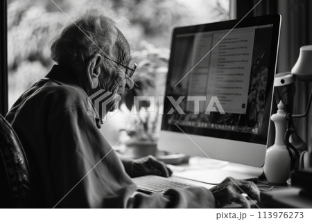 Senior person in a domestic setting, captured in grayscale while deeply focused on using a desktop computer 113976273