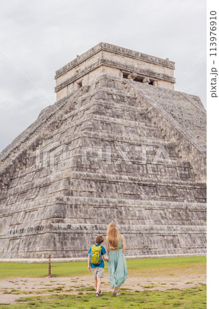 Beautiful tourist woman and her son observing the old pyramid and temple of the castle of the Mayan architecture known as Chichen Itza these are the ruins of this ancient pre-columbian civilization 113976910