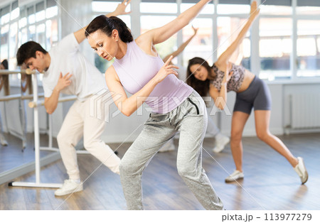 Expressive young girl learning modern street dancing during multinational group class in choreographic studio Expressive young girl learning modern street dancing during multinational group class in choreographic studio 113977279