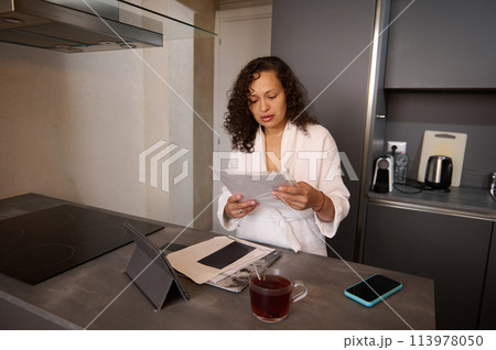 Young pretty woman handling home finances with smartphone and tablet, looking worried while going through financial bills. Financial plan, tax, spending and budgets, financial problems concept Young pretty woman handling home finances with smartphone and tablet, looking worried while going through financial bills. Financial plan, tax, spending and budgets, financial problems concept 113978050