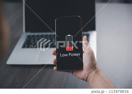 Close up man's hands using smart phone battery low charge battery screen, Businessman holding a smartphone  Low battery warning on a mobile phone. Need to connect the charger to the smartphone icon 113978658