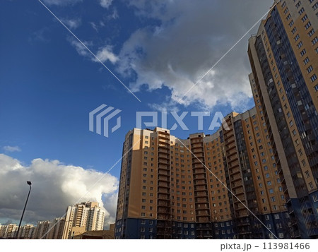 High rise buildings on a background of blue sky with white clouds. High rise buildings on a background of blue sky with white clouds. 113981466