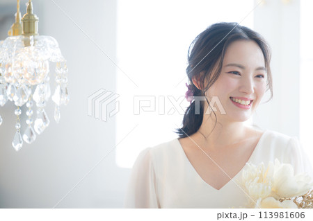 ウェディングドレスを着た若い女性　前撮りやブライダルなど花嫁の結婚式のイメージ　振り返る美しい表情 113981606