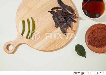 High angle shot at wooden chopping board with blank space for displaying product made from locust. Locust extract is often used in formulas for shampoos and hair conditioners High angle shot at wooden chopping board with blank space for displaying product made from locust. Locust extract is often used in formulas for shampoos and hair conditioners 113983142