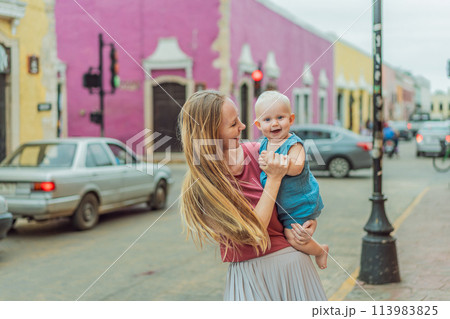 Mother and baby son tourists explore the vibrant streets of Valladolid, Mexico, immersing herself in the rich culture and colorful architecture of this charming colonial town Mother and baby son tourists explore the vibrant streets of Valladolid, Mexico, immersing herself in the rich culture and colorful architecture of this charming colonial town 113983825