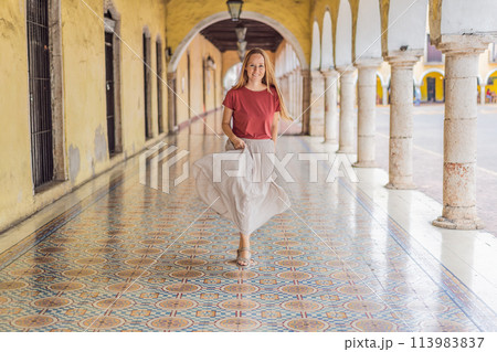 Woman tourist explores the vibrant streets of Valladolid, Mexico, immersing herself in the rich culture and colorful architecture of this charming colonial town 113983837