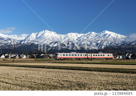 剱岳を眺めながら走る富山地方鉄道の電車 113984085