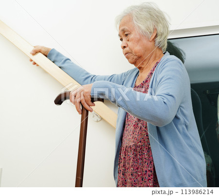 Asian senior woman use walking stick with caregiver help support walking down the stairs prevent accident, slip and fall at home. Asian senior woman use walking stick with caregiver help support walking down the stairs prevent accident, slip and fall at home. 113986214