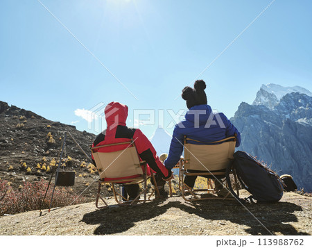 asian couple sitting in chair on top of mountain looking at view 113988762