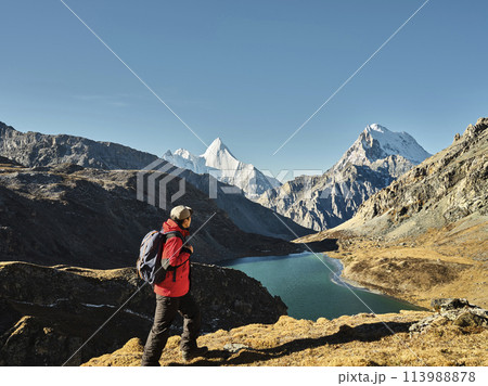 asian hiker looking at mount jampayang and chanadorje and lake boyongcuo in yading, daocheng 113988878