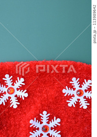 close up texture of red wool textile with white snowflake on green background, christmas decoration 113989642