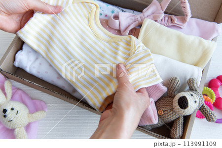 Women's hands collect children's clothes into boxes. . Women's hands collect children's clothes into boxes. . 113991109