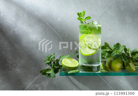 Mojito with ice, lime, and mint on a grey background. Mojito with ice, lime, and mint on a grey background. 113991300