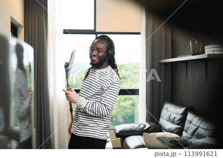 Attractive African American man enjoy doing housework, singing and dance with mop Attractive African American man enjoy doing housework, singing and dance with mop 113991621