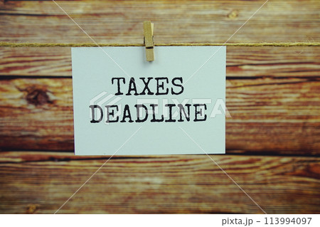Taxes Deadline text on paper card hanging on the wall with Clothespins 113994097