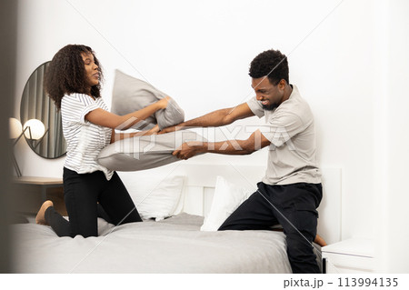 Happy Couple Having Pillow Fight in Modern Bedroom 113994135