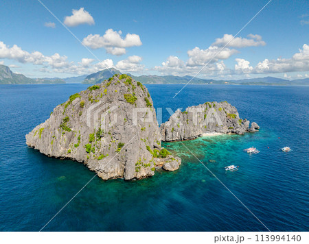 Tourist boats over the blue sea in Twin Rocks. Blue sky and clouds. El Nido, Palawan. Philippines. 113994140