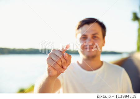 man pointing finger with positive emotion. unshaven beard young adult man shows his finger at camera on lake on sunny day. Believe in yourself concept 113994519
