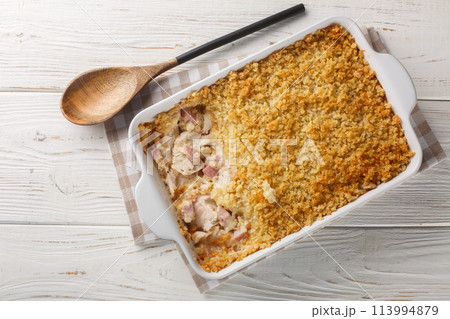 Hot Chicken Cordon Bleu Casserole has layers of chicken, ham, cheese sauce, and buttery Panko breadcrumbs close up in the baking dish. Horizontal top view 113994879