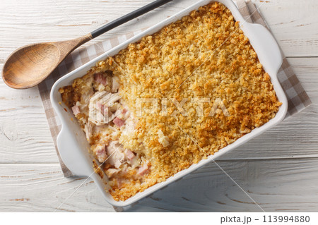 Chicken Cordon Bleu Casserole with chicken breast, chopped ham and Swiss cheese layered with creamy sauce and breadcrumbs close up in the baking dish. Horizontal top view 113994880