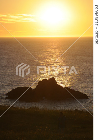 海に沈む夕日と岩のシルエット 113996063