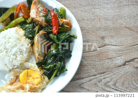spicy stir fried Chinese kale with fish can in tomato sauce topping egg on plain rice in plate 113997221
