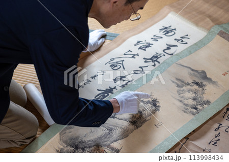 古い掛け軸の鑑定をしている男性 113998434